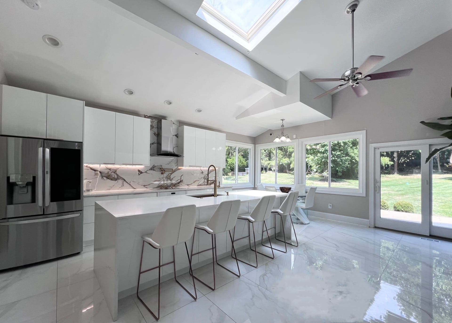 Modern Kitchen Renovation — Stunning open-concept kitchen with vaulted ceilings, marble backsplash, and sleek white cabinetry.
